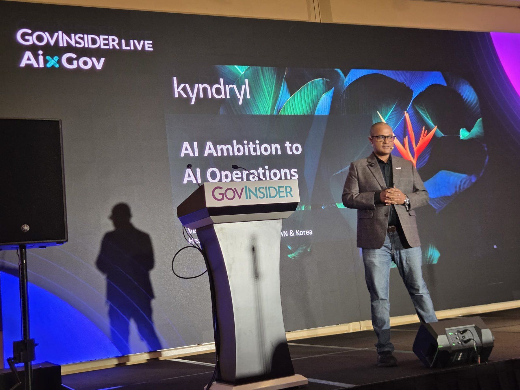 Vishnu Nanduri on the GovInsider AIxGov stage, with the talk title AI Ambition to AI Operations on screen