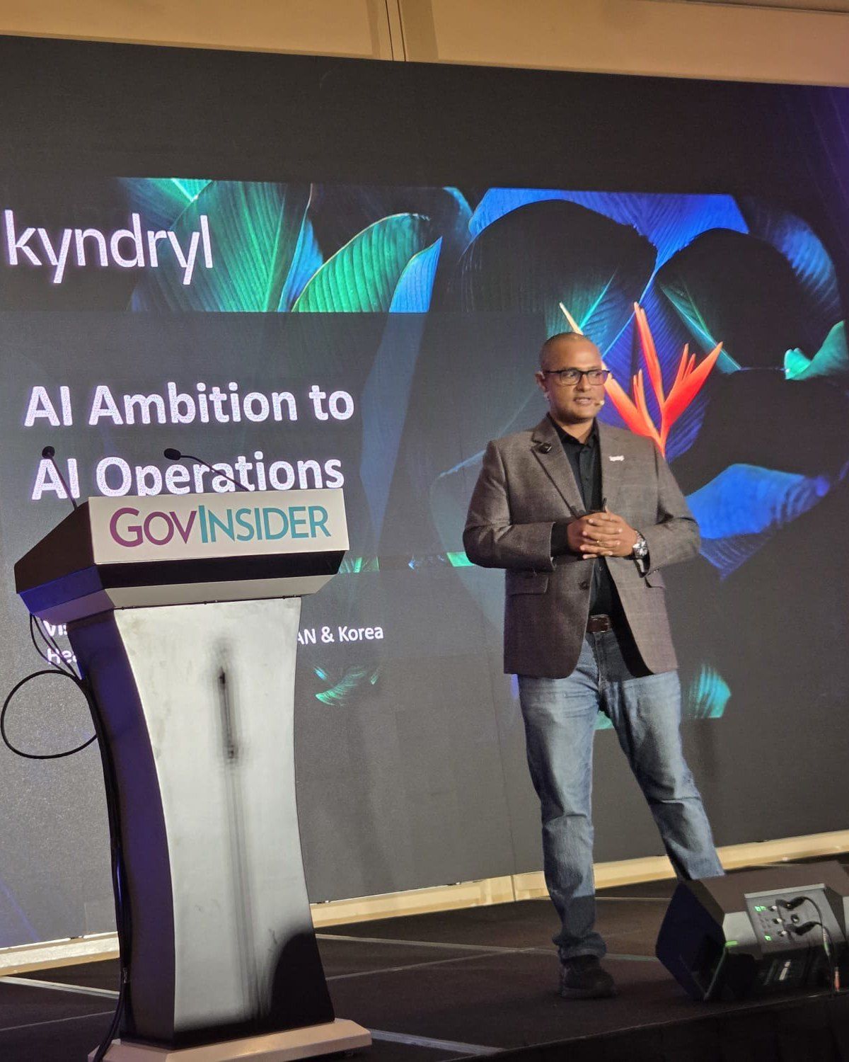 Vishnu Nanduri on stage at GovInsider AIxGov beside a screen reading AI Ambition to AI Operations