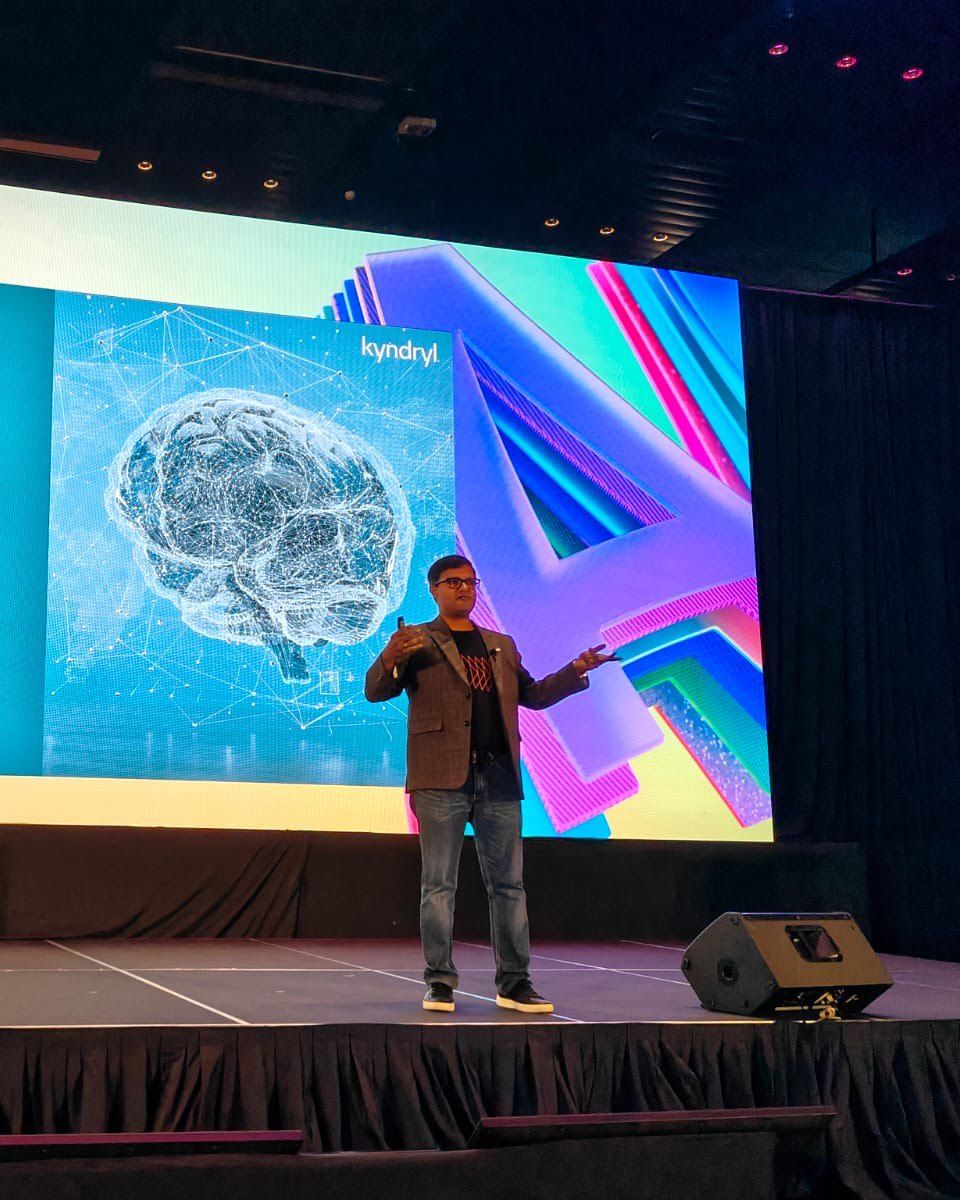 Vishnu Nanduri presenting on a large stage in front of a Kyndryl slide on combining generative AI with agentic AI