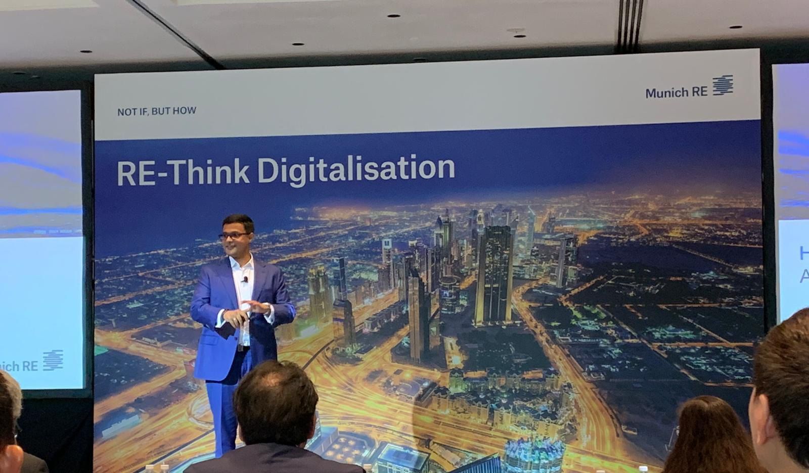 Vishnu Nanduri on stage at the Munich Re Regional CEO Summit in front of a screen reading RE-Think Digitalisation
